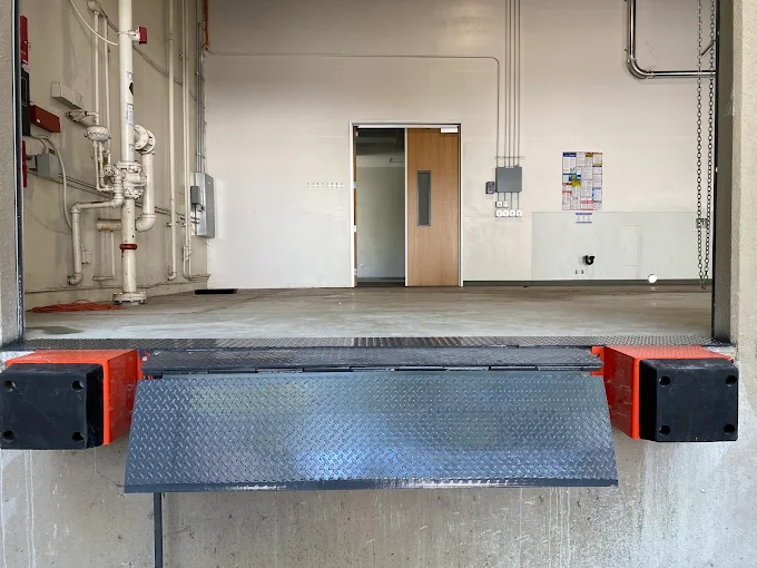 Loading dock leveler and bumpers at a commercial door opening