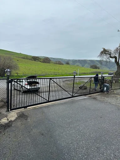 Black metal automatic gate overlooking rolling hills